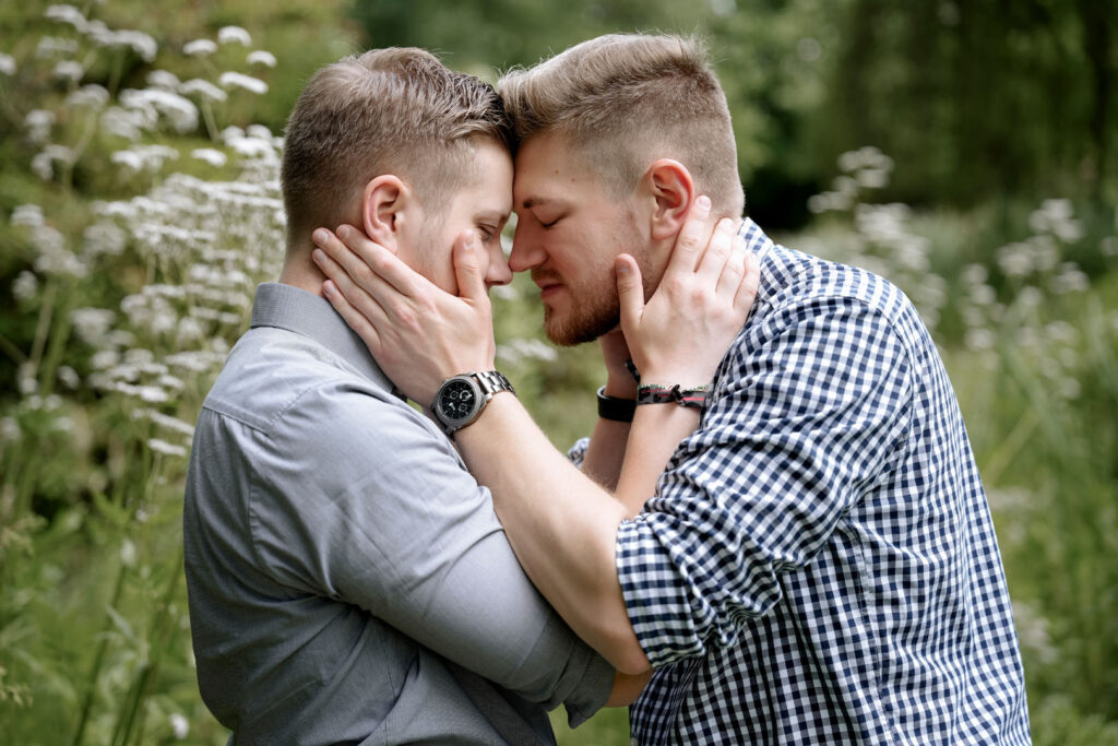 Ein glückliches Paar steht sich in wäldlicher Idylle Stirn an Stirn gegenüber.