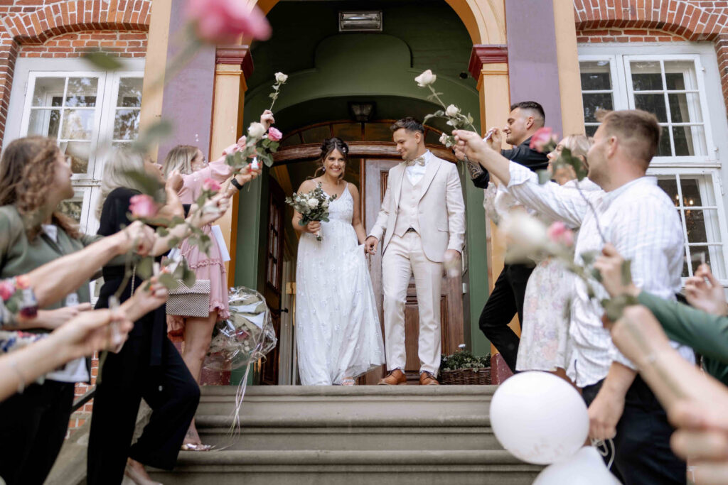 Kristina und Dennis verlassen die Kirche und werden von feiernden Freunden und Familie empfangen.