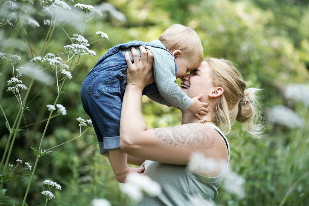 Die Mutter hält ihr Kind in schöner grüner Kulisse in den Armen.