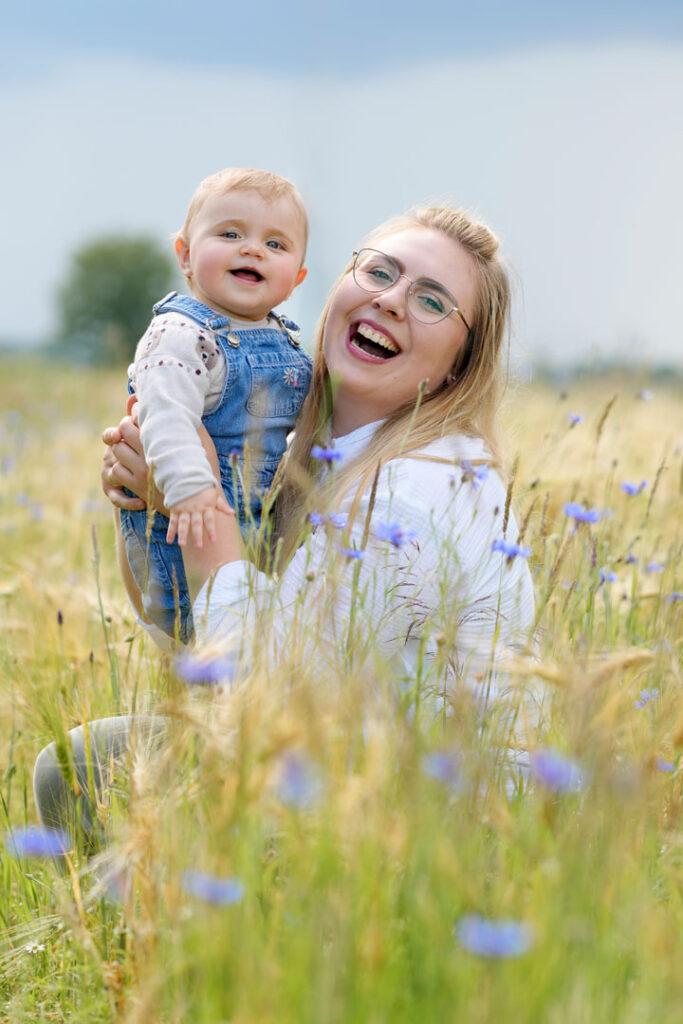 Eine lachende Mutter mit ihrem glücklichen Kind auf einer schönen Wiese.