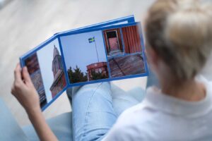 Person blättert durch ein Fotobuch mit Aufnahmen von Architektur und einer schwedischen Flagge